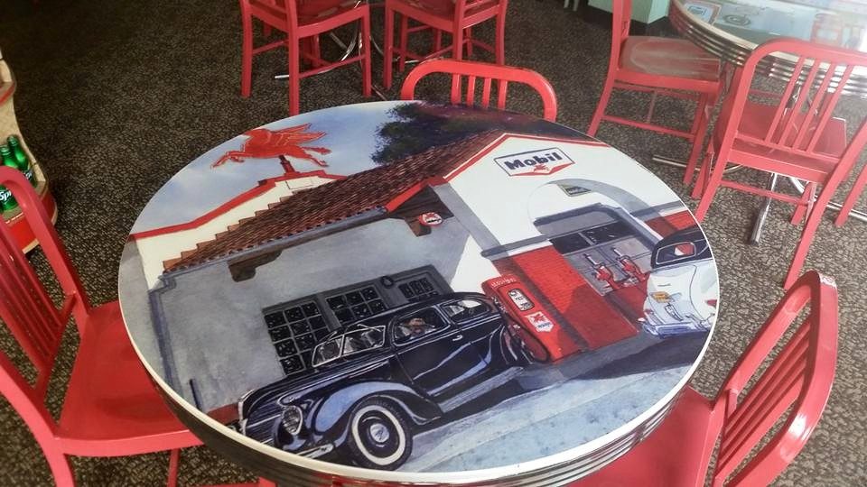 Red chairs around a table printed with a vintage gas-station scene